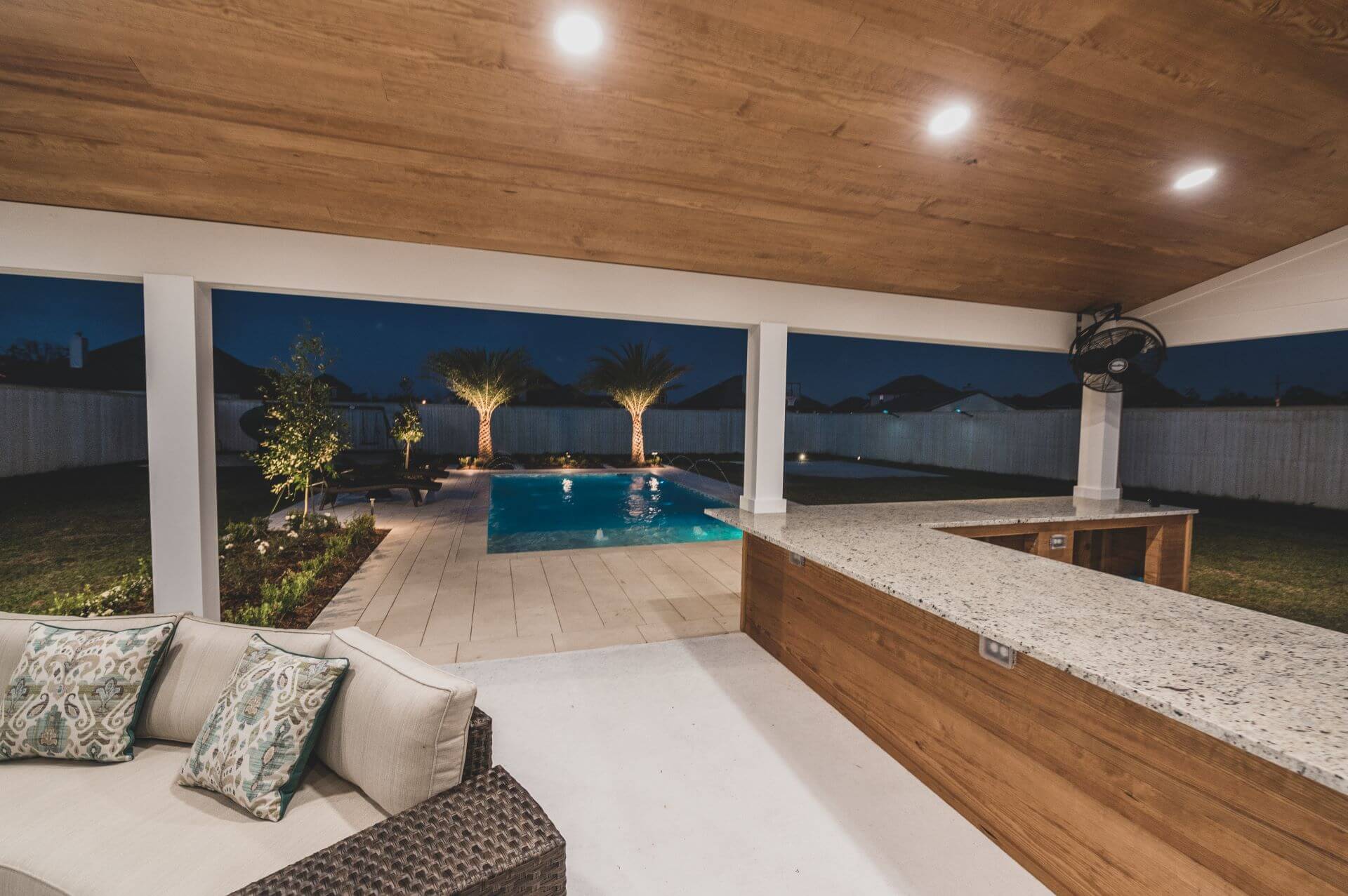 A picture of a patio, looking out towards a pool by Miller Outdoors
