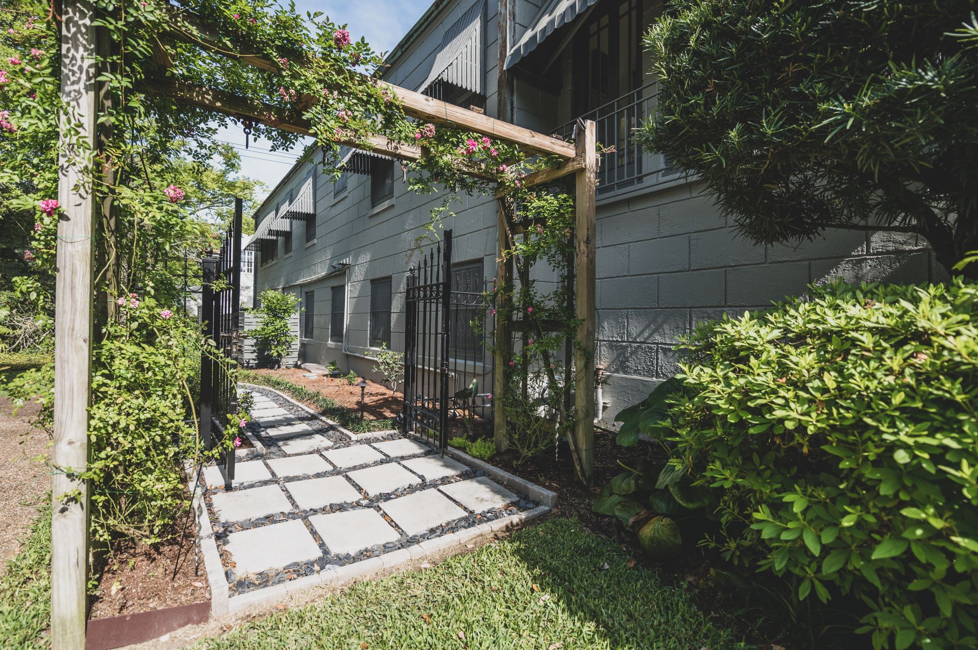 Image of a renovated backyard with pavers, bushes, and a custom trellis, completed by Miller Outdoors, a New Orleans Landscape Designer.